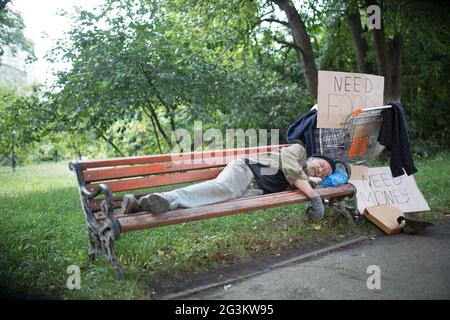 View of homeless old man on the bench in city park. Stock Photo