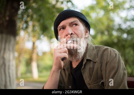 Portrait of homeless old man smoking. Stock Photo