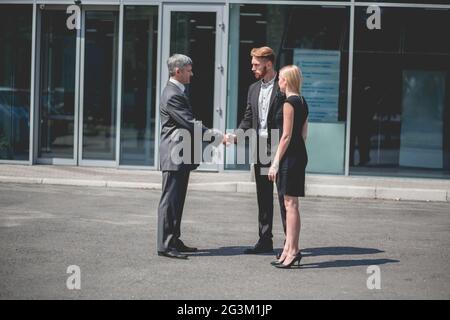 Achat d'une nouvelle voiture, d'un jeune couple et d'un directeur de véhicule devant la salle d'exposition. Banque D'Images