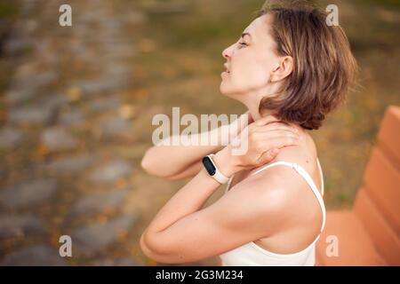 Femme souffrant de douleurs au cou dans le parc. Concept de santé et de médecine Banque D'Images