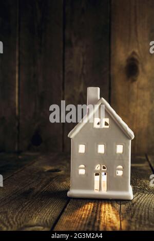 Porte-bougie en céramique blanc en forme de maison sur fond en bois Banque D'Images