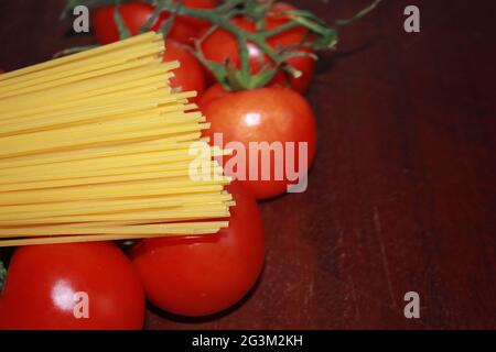 Photographie de gros plan de spaghetti et de tomates non cuits sur un fond de bois. Banque D'Images