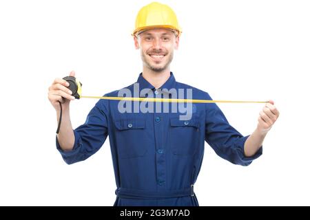 Portrait horizontal d'un beau technicien de construction caucasien portant un uniforme avec un casque de mesure de la largeur ou de la longueur de quelque chose Banque D'Images