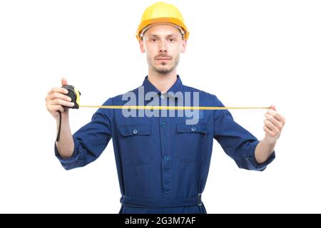 Portrait horizontal d'un beau technicien de construction caucasien portant un uniforme avec un casque de mesure de la largeur ou de la longueur de quelque chose Banque D'Images