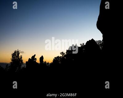 des silhouettes de randonneurs passionnés s'assoient sur un rocher pour observer le lever du soleil Banque D'Images