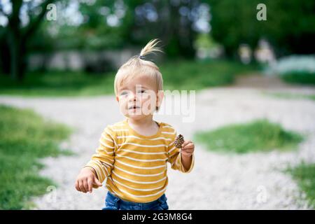 La petite fille tient un cône de pin dans sa main Banque D'Images