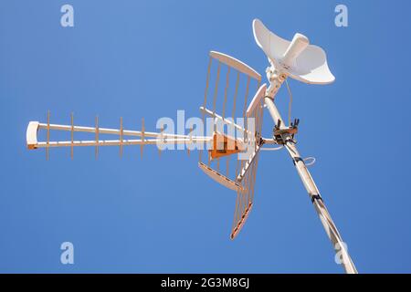 Antennes de télévision et d'Internet installées sur un mât métallique avec le ciel bleu clair en arrière-plan. Banque D'Images