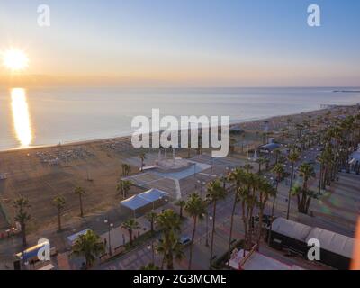 Vue aérienne supérieure donnant sur la pause de la journée à la promenade des palmiers de Finnikoudes dans la vieille ville de Larnaca, Chypre. Le soleil levant glade à la surface de la mer. Banque D'Images
