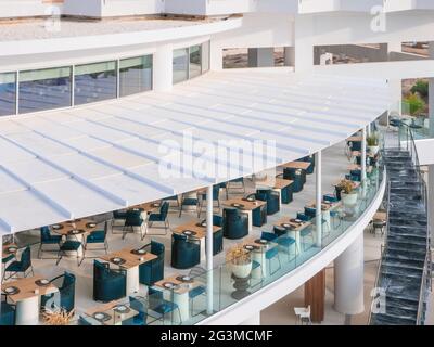 Restaurant de l'hôtel avec terrasse en plein air, tables à manger en bois et chaises bleues, offrant une vue sur la mer méditerranée à Ayia Napa Banque D'Images