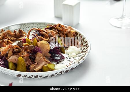 Émincé de langue de bœuf sur une assiette avec des herbes fraîches et des concombres marinés, gros plan, fond clair. Banque D'Images