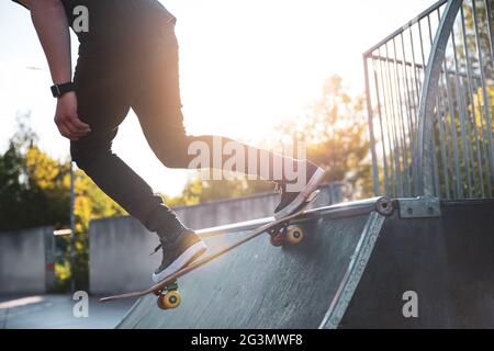 Skater tombe dans la rampe d'accès dans un parc de skate par temps ensoleillé Banque D'Images