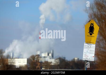 '10.02.2021, Schwedt, Brandebourg, Allemagne - panneau de parc national. En arrière-plan, les gaz d'échappement s'échappent des cheminées de la Leipa Georg Leinfelder G. Banque D'Images