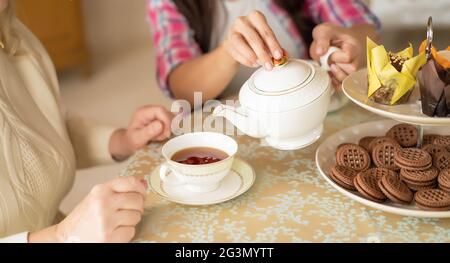 Les mains de la jeune femme avec la théière chinoise blanche versant du thé dans la tasse de sa mère âgée Banque D'Images