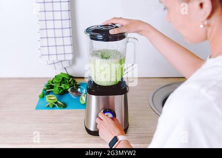 Femme fait maison smoothie saine. Cocktail vert végétarien à base d'épinards, de brocoli et de lait de coco. Supplément de vitamine le matin. Vie saine Banque D'Images