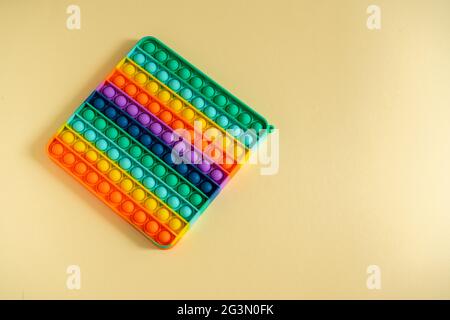 Grand popit isolé sur fond jaune. Silicone brillant rayé jouet grand Pop IT gros plan. POPIT pour les enfants appuyant les bulles avec ses doigts, haut Banque D'Images