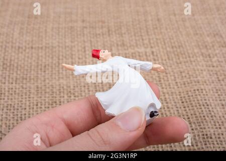Main tenant une figurine de couleur blanche Sufi Dervish Banque D'Images