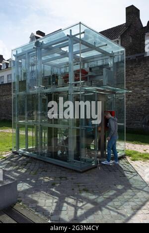 Les gens entrent dans un ascenseur en verre au-dessus du sol qui mène à un garage de stationnement. En arrière-plan le mur historique de la ville de Maastricht Banque D'Images