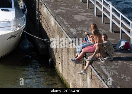 Deux filles et un garçon sont assis sur le bord d'un mur de quai le long de la rivière Maas à Maastricht un chaud jour d'été et de manger une glace Banque D'Images