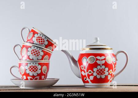 Pile de tasses en céramique antique et théière sur une table en bois contre un mur blanc Banque D'Images