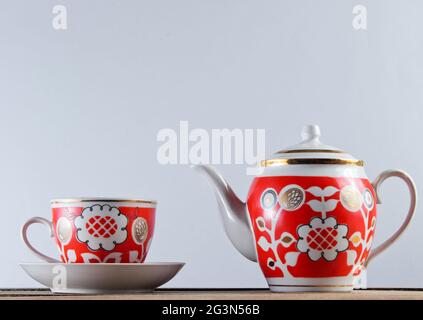 Tasse en céramique antique et théière sur une table en bois contre un mur blanc Banque D'Images
