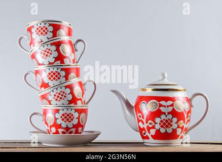 Pile de tasses en céramique antique et théière sur une table en bois contre un mur blanc Banque D'Images