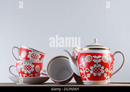 Tasses en céramique antique et théière sur une table en bois contre un mur blanc Banque D'Images