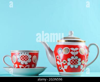 Tasse en céramique antique et théière sur une table en bois contre un mur bleu Banque D'Images