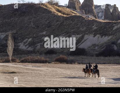 Les touristes en équitation sur les chevaux safari avec le paysage de cheminées de fées à Cappadoce, Turquie Banque D'Images