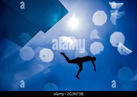 Cologne, Allemagne. 17 juin 2021. Un athlète de loisirs saute d'une tour de plongée de 7 1/2 mètres dans une piscine à la piscine du stade en plein soleil sur un ciel bleu. Credit: Rolf Vennenbernd/dpa/Alay Live News Banque D'Images