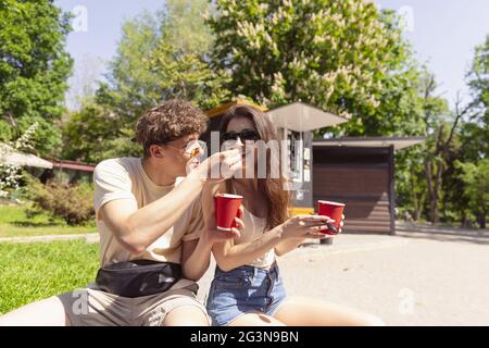 Joyeux jeune couple séduisant romantiquement en train de manger une pizza fraîche à l'extérieur. Banque D'Images