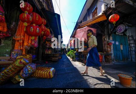 Une femme tenant un parapluie passe devant l'entrée d'une allée à Chinatown, Bangkok, Thaïlande Banque D'Images