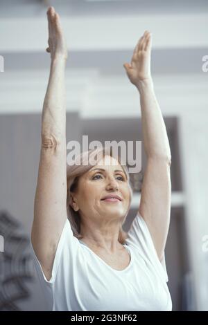 Belle femme de plus de 50 ans aime faire du yoga à la maison. Banque D'Images