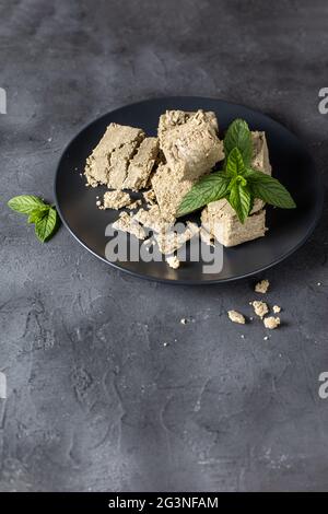 Morceaux de halva sur plaque noire. Dessert turc doux avec feuilles de menthe sur fond noir Banque D'Images