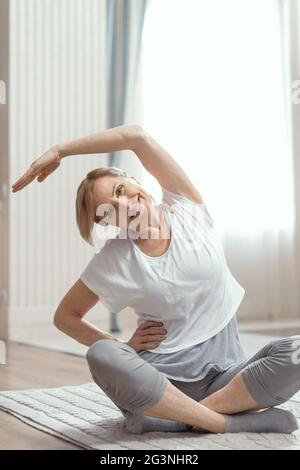 Des cours de yoga à la maison de belles femmes de plus de 50 ans. Banque D'Images