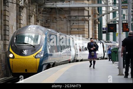 Un joueur de cornemuse parcourt la plate-forme le long du train Avanti West Coast Class 390 EMU qui arrive à la gare centrale de Glasgow depuis Londres Euston, sans avoir réussi à battre le record de 36 ans pour le trajet le plus rapide entre Londres et Glasgow. Le train Royal Scot est arrivé à Glasgow Central 21 secondes après le record de trois heures, 52 minutes et 40 secondes établi par British Rail en décembre 1984 Date de la photo : jeudi 17 juin 2021. Banque D'Images