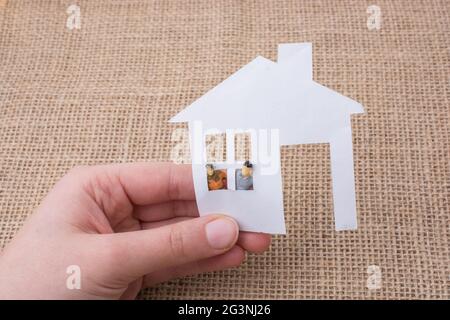 Maison de papier et un homme figurine sur un fond de toile Banque D'Images