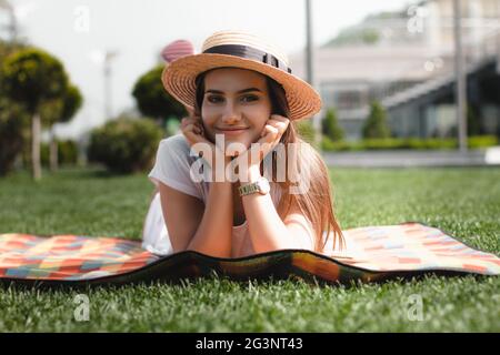 Belle jeune fille est posée sur la couverture dans le parc et de sourire. Banque D'Images