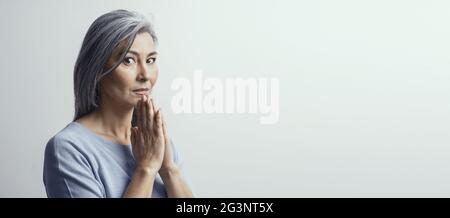 Mature Asian woman praying sur fond blanc Banque D'Images