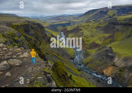 Vue aérienne de l'homme se tenant sur le bord de la falaise en profitant de la vallée des montagnes de l'Islande et de la cascade de Haifoss Banque D'Images