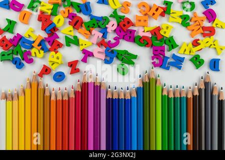 crayons de couleur en bois et lettres de l'alphabet anglais sur fond blanc, espace de copie Banque D'Images