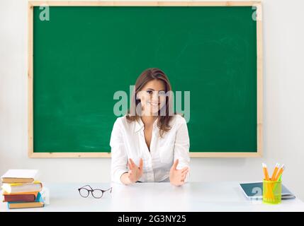 Retour à l'école. Un enseignant avec des lunettes regarde la caméra sur le fond d'une commission scolaire dans une classe scolaire. Banque D'Images