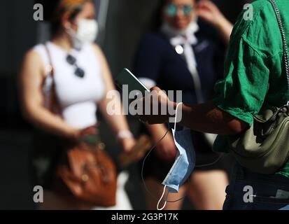(210617) -- PARIS, le 17 juin 2021 (Xinhua) -- UNE femme portant son masque sur des promenades au poignet sur l'avenue des champs-Elysées à Paris, France, le 17 juin 2021. Le Premier ministre français Jean Castex a annoncé mercredi que les gens pourraient cesser de porter des masques à l'extérieur à partir de jeudi et que le couvre-feu de nuit sera également levé à partir de dimanche, les indicateurs COVID-19 du pays continuant à baisser. (Xinhua/Gao Jing) Banque D'Images