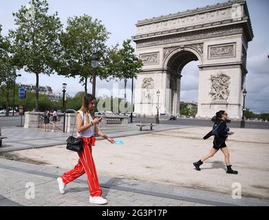 (210617) -- PARIS, le 17 juin 2021 (Xinhua) -- UNE femme tenant son masque à la main marche près de l'Arc de Triomphe à Paris, France, le 17 juin 2021. Le Premier ministre français Jean Castex a annoncé mercredi que les gens pourraient cesser de porter des masques à l'extérieur à partir de jeudi et que le couvre-feu de nuit sera également levé à partir de dimanche, les indicateurs COVID-19 du pays continuant à baisser. (Xinhua/Gao Jing) Banque D'Images