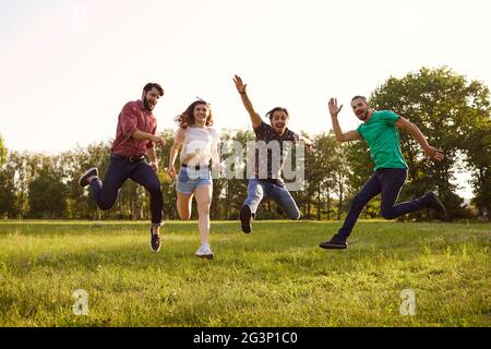 De jeunes amis heureux sautant ensemble à l'extérieur. Groupe de personnes s'amusant pendant les vacances d'été dans la campagne Banque D'Images