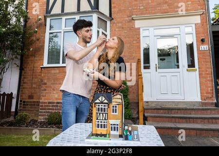 UTILISATION ÉDITORIALE SEULEMENT les acheteurs de première fois, George Isaacs et Lauren Turner se voient présenter un gâteau de célébration ÔFirst-HomeÕ à l'extérieur de leur nouvelle maison à Redditch, Créé par Ben Cullen, le Bake King, pour aider les nouveaux propriétaires à marquer leur étape dans l'achat de leur maison, alors que des recherches de Halifax ont révélé qu'un cinquième des Britanniques dépenseraient moins pour un mariage depuis la pandémie et que d'autres priveraient l'achat d'une première maison. Même si les couples considèrent l'achat d'une maison comme un engagement plus important qu'un mariage, seuls les deux cinquièmes des jeunes envisageraient de célébrer la réussite avec leurs proches. Banque D'Images