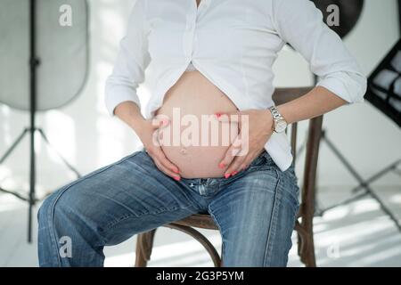 Femme mains serrant le ventre. Photoset en studio. Banque D'Images