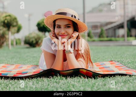 Belle jeune fille est posée sur la couverture dans le parc et de sourire. Banque D'Images