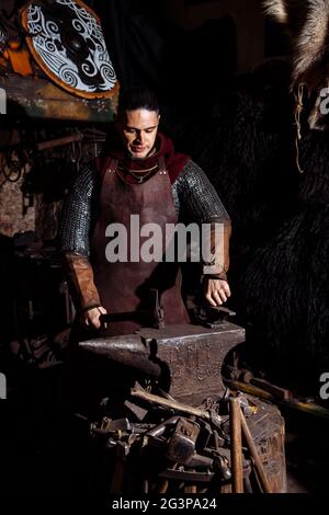 Viking forge des armes et des épées dans le smithy. Un homme dans les vêtements d'un guerrier est dans le smithy Banque D'Images