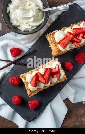 Fraises, framboises et crème mille feuille sur assiette en pierre noire Banque D'Images