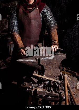 Viking forge des armes et des épées dans le smithy. Un homme dans les vêtements d'un guerrier est dans le smithy Banque D'Images